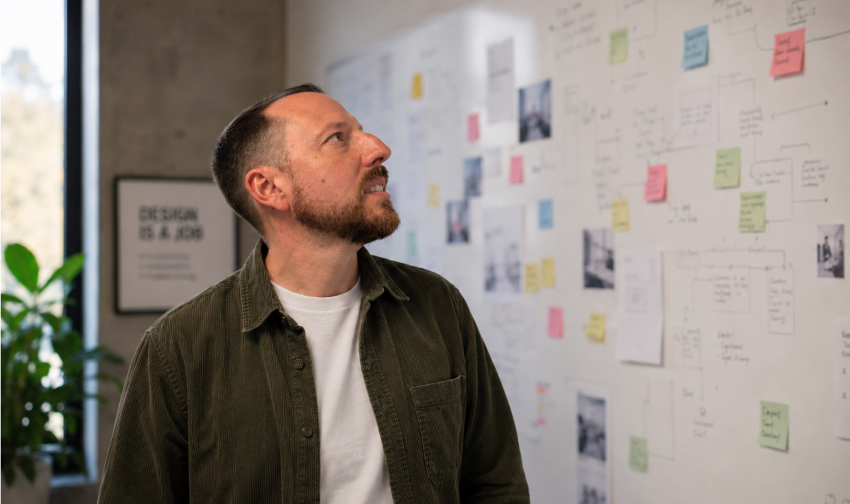Michael Cattell standing in front of a wall covered in workshop notes and sketches